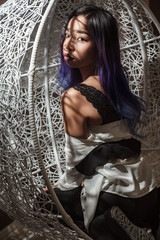 beautiful asian woman sitting in hanging rattan chair