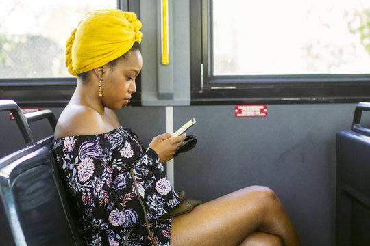 Side view of young woman using smartphone in bus