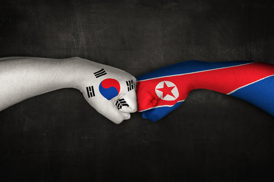 Fist bumping with painted flags of South Korea and North Korea.