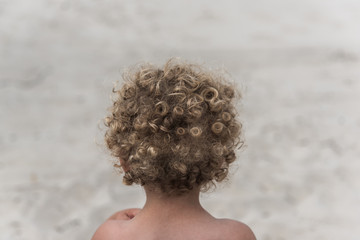 Back of blonde white male toddler with curly hair. 