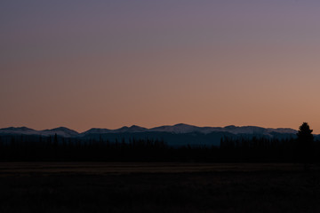 Sunset landscape overlooking a meadow and mountains in silhouette in Colorado's Rocky Mountain National Park. 