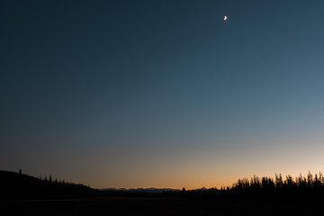 Silhouette night landscape with moon overlooking a meadow in Colorado's Rocky Mountain National Park. 