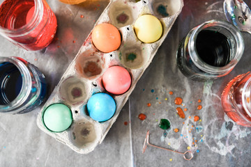 Top view of multi-colored eggs drying in a cardboard egg container on top of parchment paper.