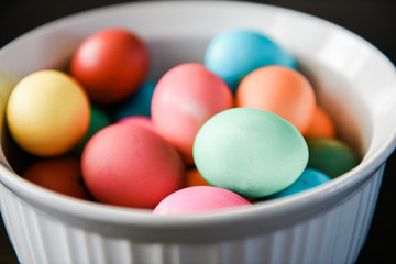 Multi-colored dyed eggs in a white bowl.