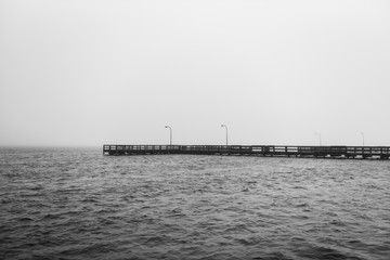 Black and white view of a dock in the Long Island, New York's Great South Bay on a cloudy morning.