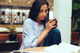 Young businesswoman reading a book while having coffee