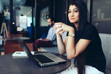 Young businesswoman having coffee while sitting in office