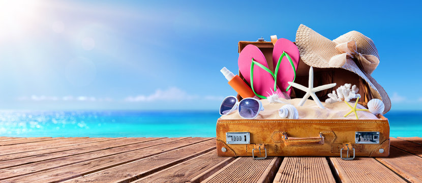 Beach Accessories In Suitcase On Wooden Pier - Travel Concept
