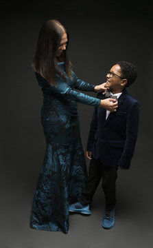 Mom fixing sons  bow tie against black background