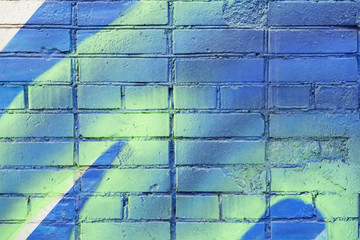 Several painted bricks in blue and yellow colors on an old dirty wall, as graffiti. Colorful grunge texture of wall. Abstract modern background