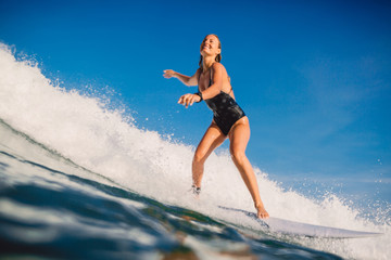 Fototapeta premium Surfer woman at surfboard ride on ocean wave. Woman in ocean during surfing.