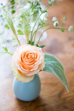 Sweet bud vase arrangement of one peach rose with lush greenery
