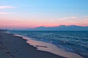 sunset seascape. blue sea and mountains. pink reflection on water surface. gradient sky