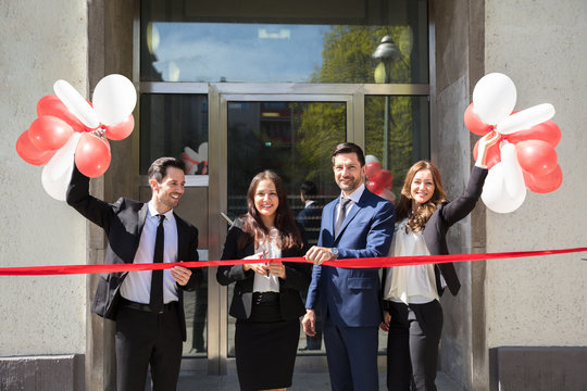 Businesspeople Cutting Red Ribbon