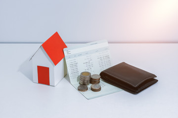 saving account passbook or financial statement, paper house model, and coins on office desk table.