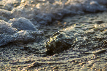 pebble stones on the sea beach, the rolling waves of the sea with foam
