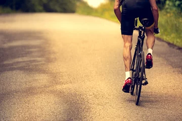 Crédence de cuisine en verre imprimé Vélo Cyclist rides a bicycle on an asphalt road. Sunset.