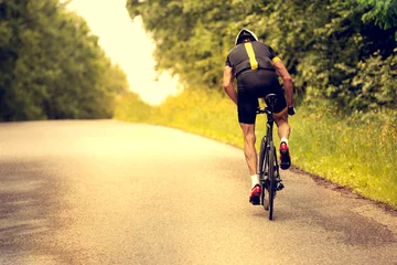 Photo sur Plexiglas Vélo Cyclist rides a bicycle on an asphalt road. Sunset.