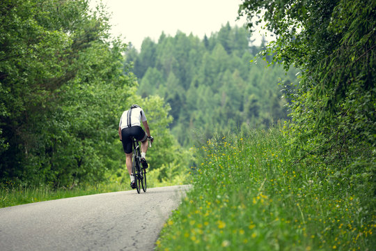 Cyclist rides a bicycle on an asphalt road.