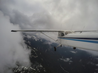 Fototapeta na wymiar Airplane flying over the beautiful Canadian Mountain Landscape during a cloudy evening. Taken North of Vancouver, British Columbia, Canada.