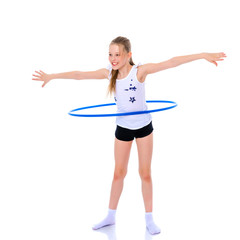 Fototapeta na wymiar A girl gymnast performs an exercise with a hoop.