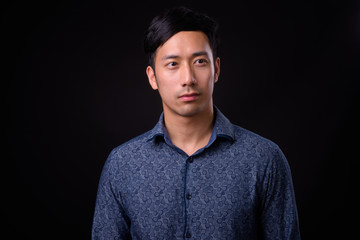 Fototapeta premium Young handsome Asian businessman against black background