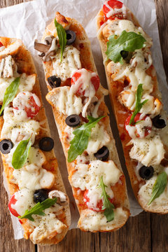 Delicious hot sandwich casserole pizza with chicken, cheese, tomatoes, olives and mushrooms close-up. Vertical top view