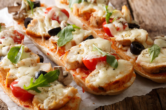 Homemade sandwich pizza baguette baked with chicken, cheese, tomatoes, olives and mushrooms close-up. horizontal