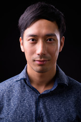 Obraz premium Young handsome Asian businessman against black background