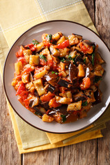 Warm salad from aubergines, tomatoes and garlic close-up. Vertical top view