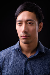 Young handsome Asian businessman against black background