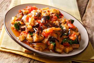 Rustic salad of fried eggplant, tomato and garlic with spices and parsley closeup. horizontal
