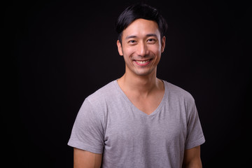 Young handsome Asian man against black background