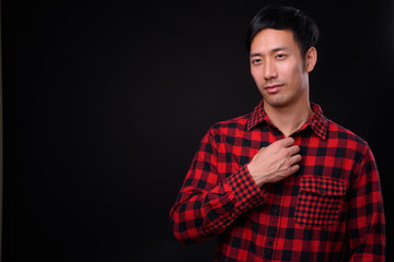 Young handsome Asian man against black background