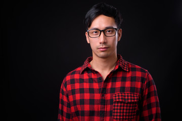 Young handsome Asian man against black background