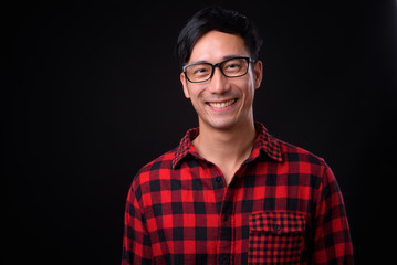 Young handsome Asian man against black background