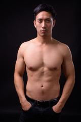 Fototapeta premium Young handsome Asian man shirtless against black background