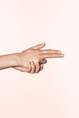 cropped image of female hands shaped in form of gun isolated on pink background