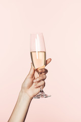 cropped shot of woman cheering by champagne glass isolated on pink background