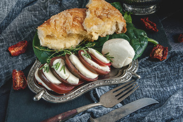 Italian Focaccia bread with cheese, rosemary, mozzarella cheese and tomatoes. Selective focus. Close-up.