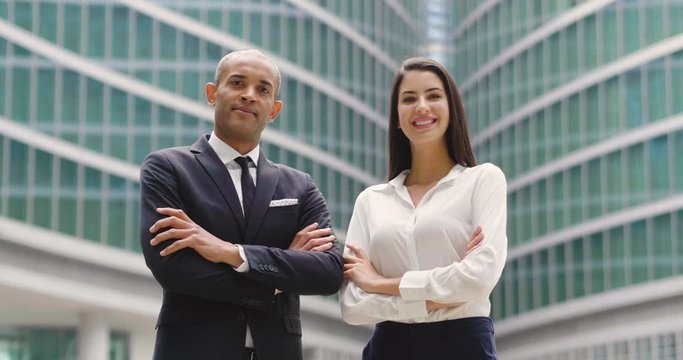 Portrait of a business man and woman of different ethnicity, looking at the camera and smiling, crossing their arms. Concept of: success, finance and team and cooperation.