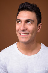 Obraz premium Young handsome Hispanic man against brown background