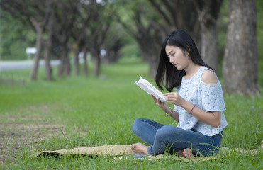 Asian women sit reading at the park.