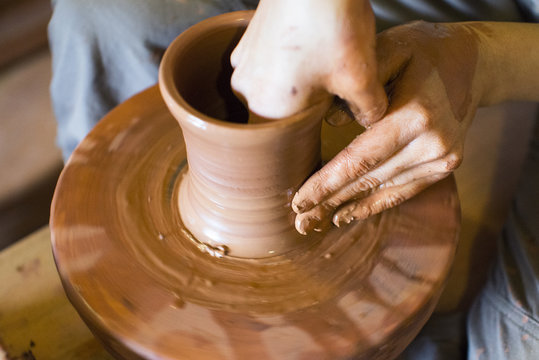 hands of a potter, creating an earthen jar on the circle.