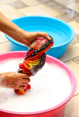 Closeup of outdoor colored clothes washing by woman's hands in sunny day. Vertical view.