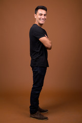 Young handsome Hispanic man against brown background