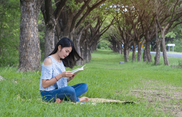 Naklejka na ściany i meble Asian women sit reading at the park.