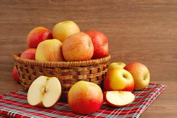 Harvest of apples in a wicker basket. Many colorful apples in a large wicker basket on a wooden background. Fruits are collected in the garden.