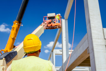 Worker is helping crane from the ground, keep balance and direction