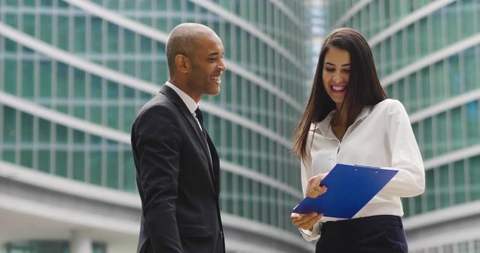 A business man and woman of different ethnicities talk about finance looking at the graphics of economic markets and banks. Concept of: success, finance and team and cooperation.